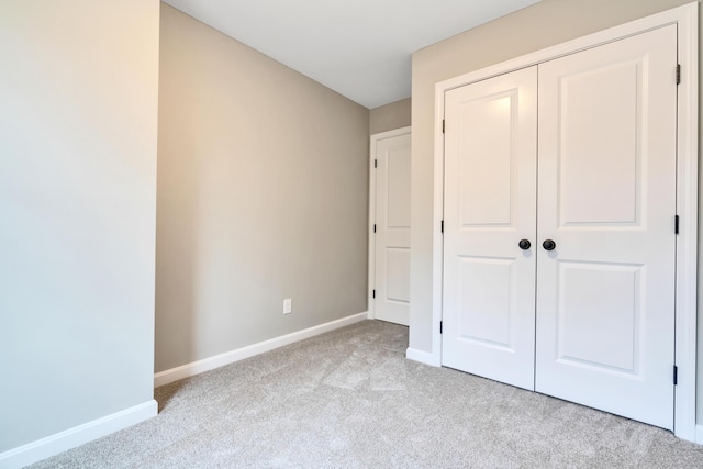 unfurnished bedroom featuring light carpet and a closet