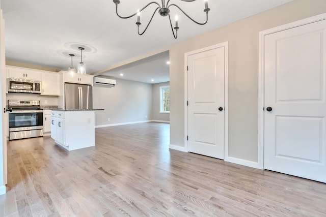 kitchen with white cabinetry, a center island, stainless steel appliances, a wall unit AC, and pendant lighting