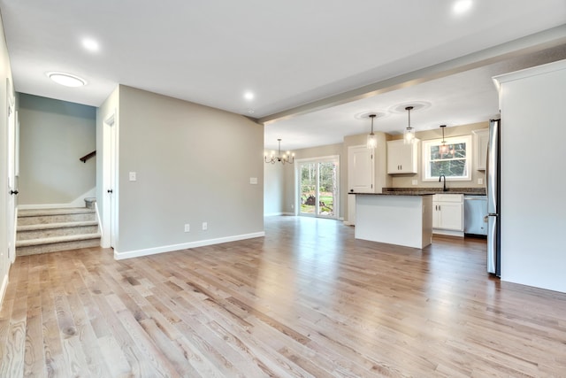 unfurnished living room featuring light hardwood / wood-style flooring, an inviting chandelier, and sink