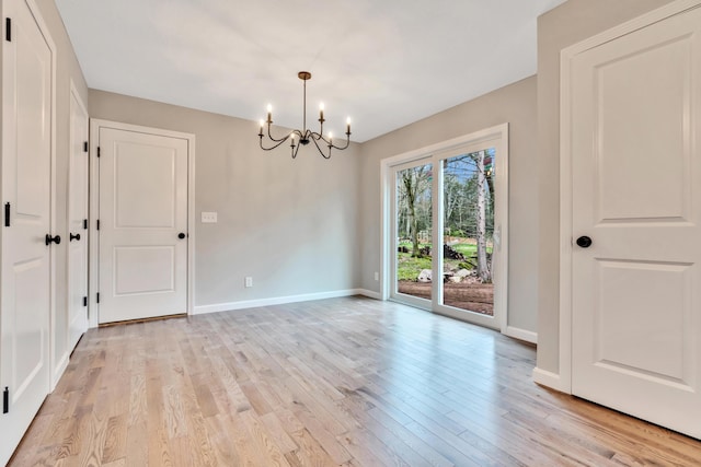 unfurnished room featuring light hardwood / wood-style flooring and an inviting chandelier