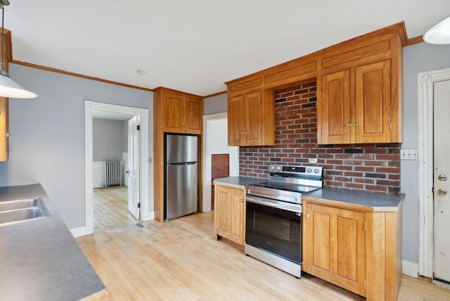 kitchen with radiator, stainless steel appliances, crown molding, sink, and light hardwood / wood-style floors