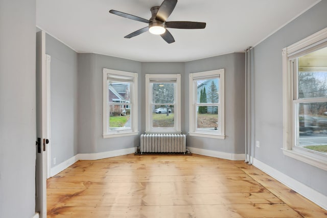 empty room with hardwood / wood-style flooring, radiator, and ceiling fan