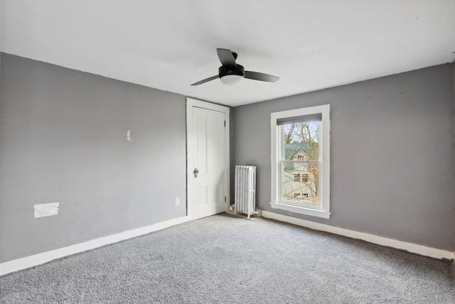 carpeted empty room with ceiling fan and radiator