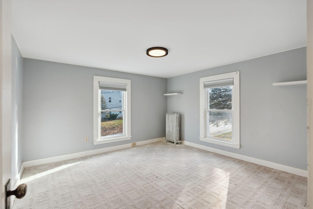 unfurnished room featuring radiator, light carpet, and a healthy amount of sunlight