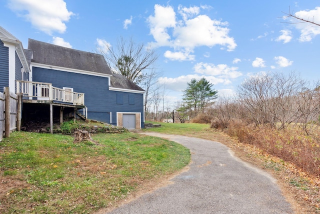 view of property exterior featuring a yard, a deck, and a garage