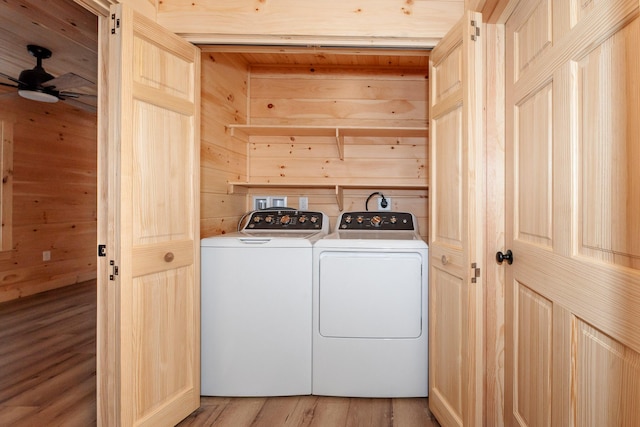 laundry room with wooden walls, light hardwood / wood-style flooring, washer and dryer, and ceiling fan