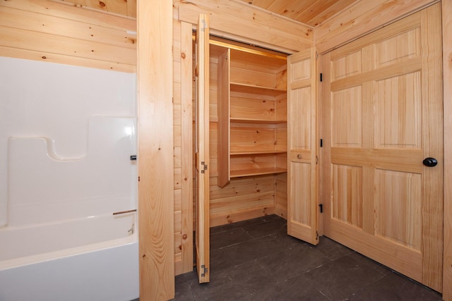 bathroom with a tub and wood walls