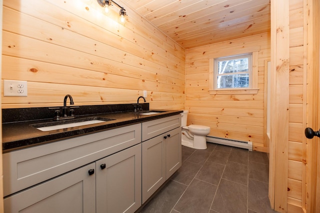 bathroom with a baseboard radiator, tile patterned floors, vanity, toilet, and wood walls