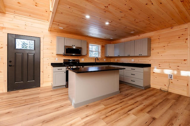 kitchen with a kitchen island, light wood-type flooring, gray cabinetry, and appliances with stainless steel finishes