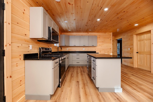 kitchen featuring light hardwood / wood-style floors, wooden ceiling, a kitchen island, stainless steel appliances, and wood walls