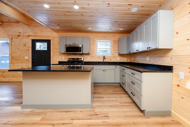 kitchen with stainless steel appliances, a center island, wood walls, and wooden ceiling