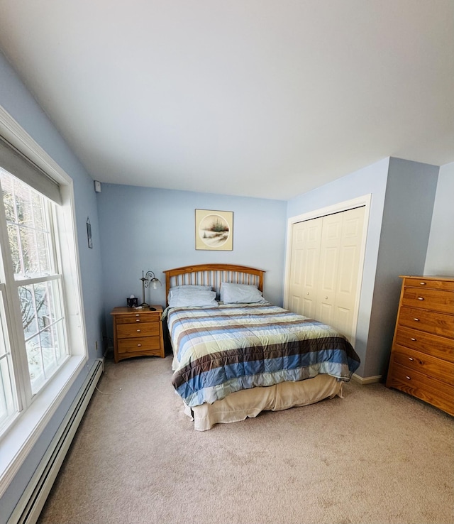 carpeted bedroom featuring a baseboard heating unit and a closet