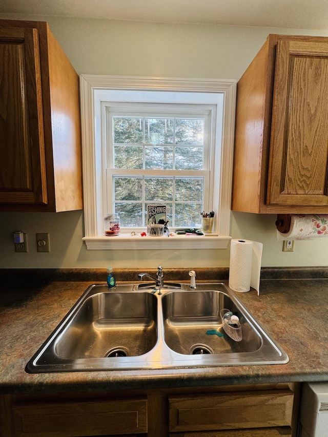 kitchen featuring a sink, brown cabinets, and dark countertops