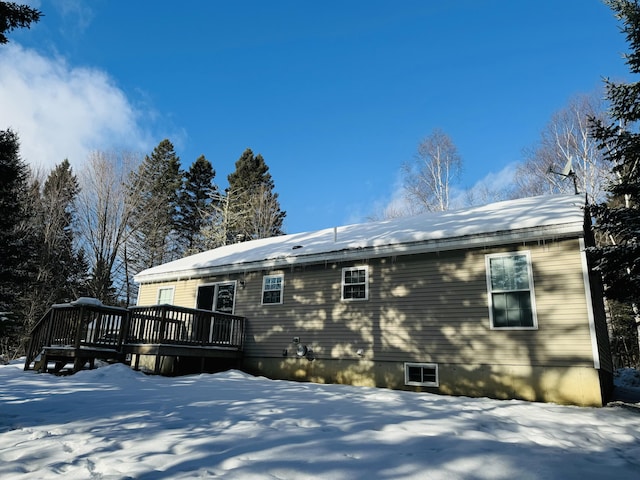 snow covered back of property featuring a wooden deck