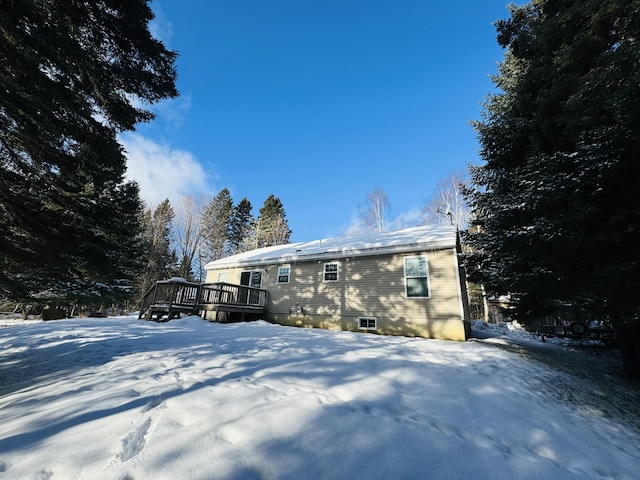 snow covered rear of property with a deck