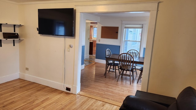 dining space featuring light wood-type flooring and ornamental molding