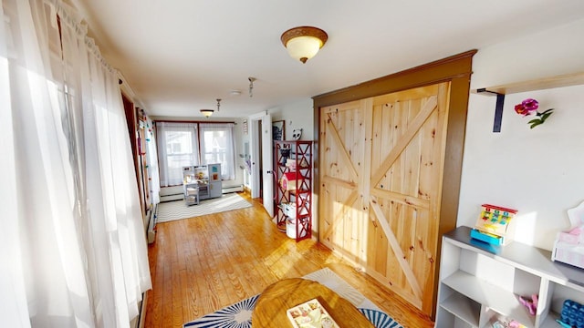 hall with light hardwood / wood-style flooring and a baseboard heating unit