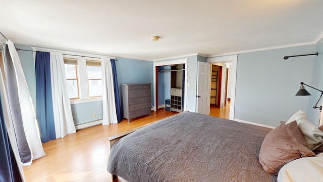 bedroom featuring a baseboard radiator, light hardwood / wood-style flooring, and crown molding