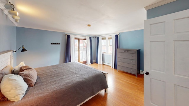 bedroom featuring a baseboard radiator, light hardwood / wood-style flooring, and crown molding