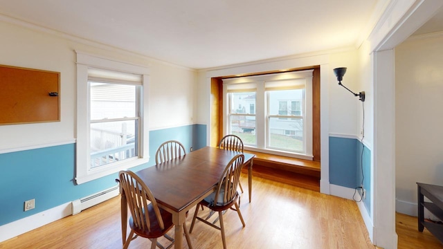 dining room featuring ornamental molding, light hardwood / wood-style flooring, and a baseboard heating unit