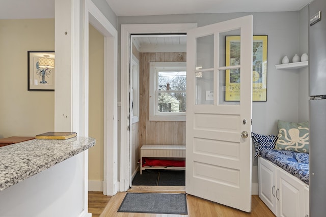 doorway to outside with wood walls and light wood-type flooring