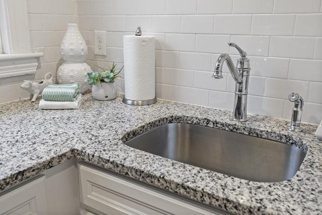 details featuring decorative backsplash, light stone counters, and sink