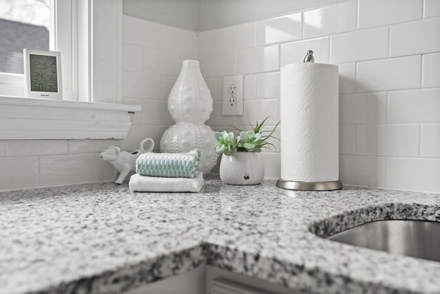 details featuring decorative backsplash, light stone counters, and white cabinetry