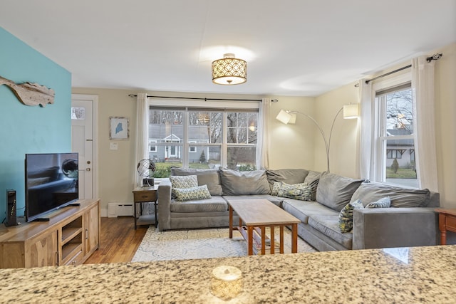 living room with a baseboard heating unit and hardwood / wood-style flooring