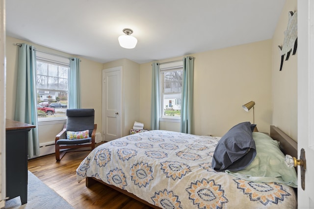 bedroom with a baseboard heating unit and hardwood / wood-style flooring