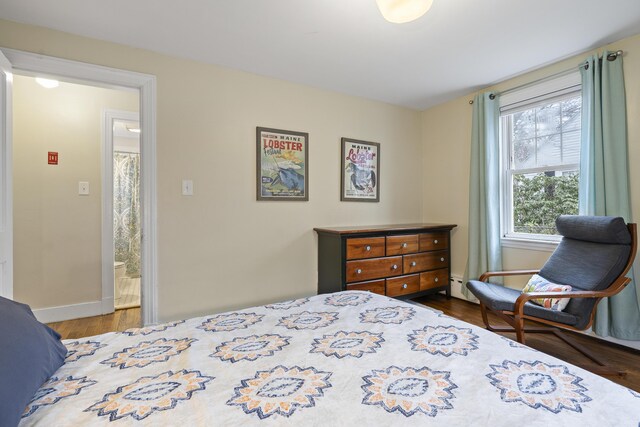 bedroom with dark hardwood / wood-style flooring and a baseboard radiator