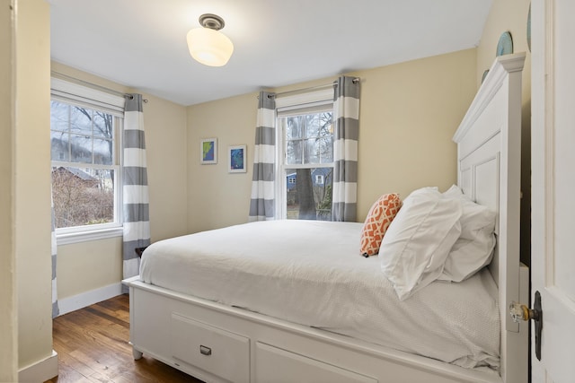 bedroom with dark hardwood / wood-style floors and multiple windows