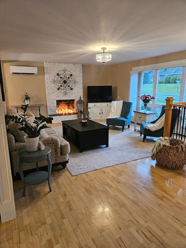 living room featuring a chandelier, light wood-type flooring, a brick fireplace, and a wall mounted AC