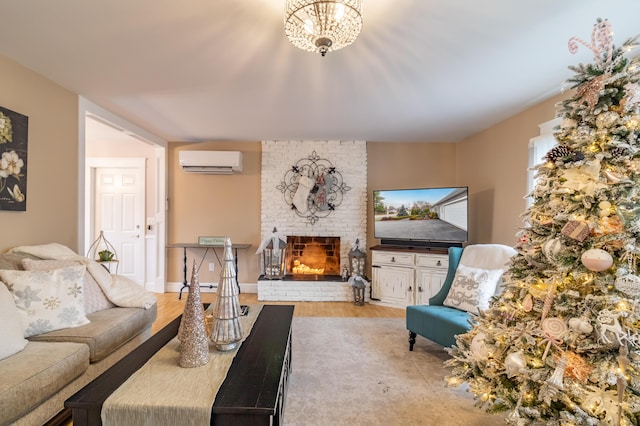 living room with an inviting chandelier, an AC wall unit, light hardwood / wood-style flooring, and a brick fireplace