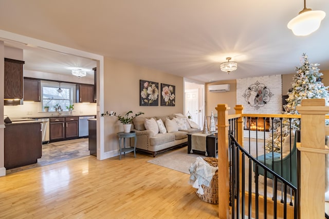 living room with light wood-type flooring, an inviting chandelier, and a wall mounted AC