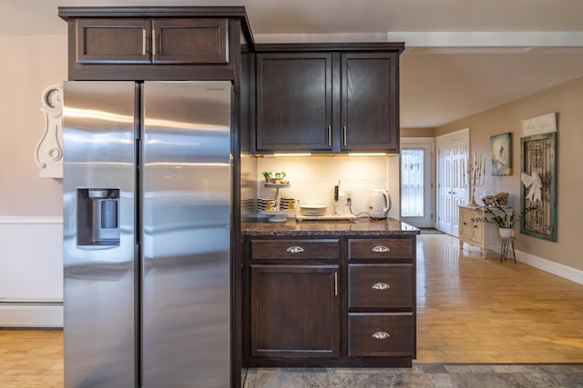 kitchen featuring dark brown cabinets, dark stone countertops, stainless steel fridge with ice dispenser, and baseboard heating