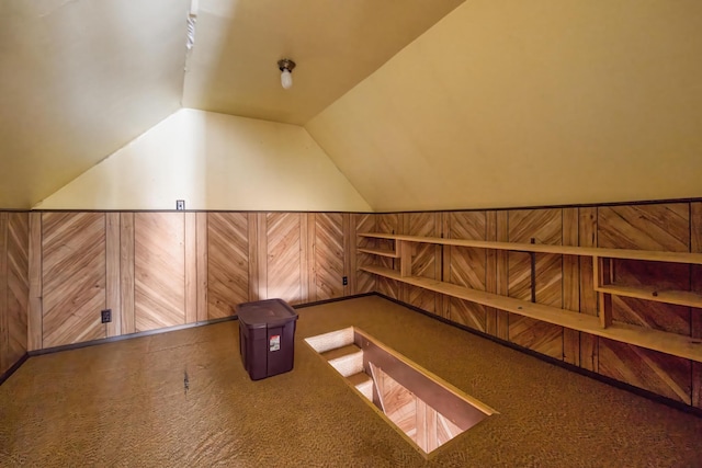 bonus room featuring carpet flooring, wood walls, and vaulted ceiling