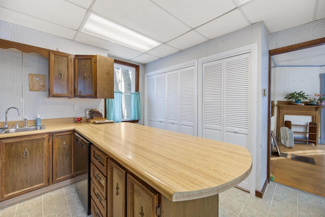 kitchen with black dishwasher, a paneled ceiling, kitchen peninsula, and sink