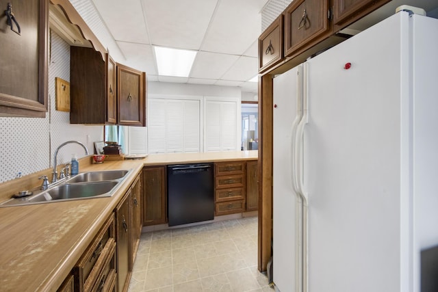 kitchen with a drop ceiling, sink, dishwasher, white fridge, and plenty of natural light