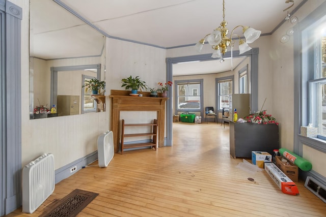 interior space featuring radiator, crown molding, light hardwood / wood-style flooring, and a notable chandelier