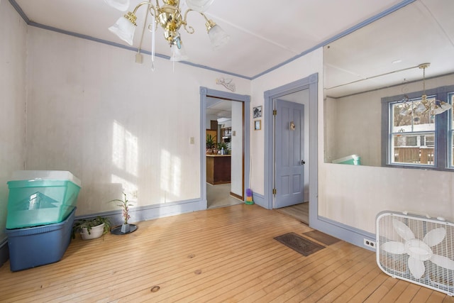 interior space with hardwood / wood-style flooring, crown molding, and a notable chandelier