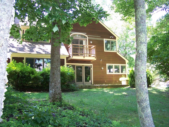 rear view of property with a balcony and a lawn