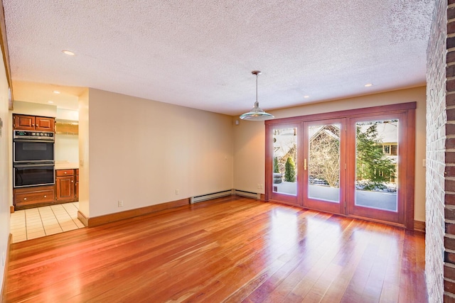 unfurnished living room with a textured ceiling, light wood-type flooring, and a baseboard radiator