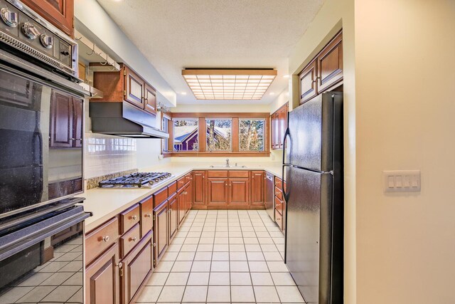 kitchen with light tile patterned floors, sink, a textured ceiling, and black appliances