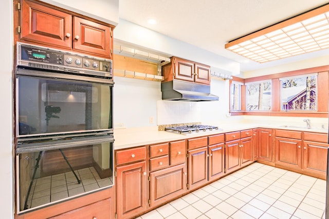 kitchen featuring sink, light tile patterned floors, black double oven, and stainless steel gas cooktop