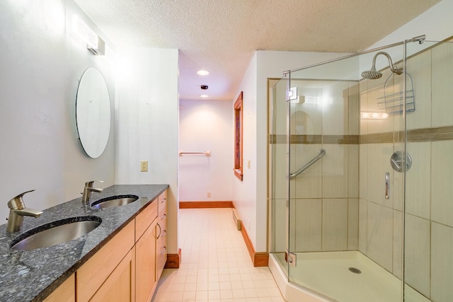 bathroom featuring tile patterned floors, vanity, a shower with shower door, and a textured ceiling