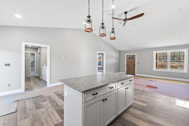 kitchen featuring light stone countertops, ceiling fan, hanging light fixtures, vaulted ceiling, and hardwood / wood-style flooring