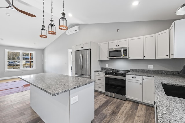 kitchen with a kitchen island, white cabinets, hanging light fixtures, and appliances with stainless steel finishes