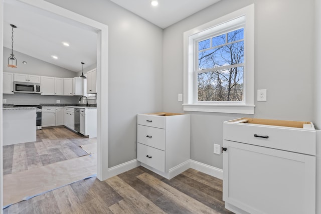 interior space with sink, dark hardwood / wood-style floors, pendant lighting, white cabinets, and appliances with stainless steel finishes