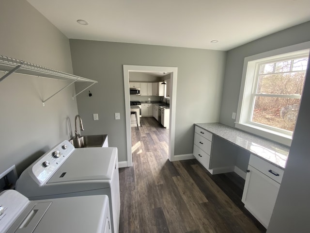 laundry area featuring washing machine and clothes dryer, dark hardwood / wood-style flooring, and sink