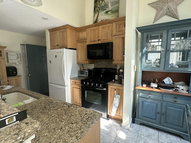 kitchen with black appliances, light tile patterned flooring, a textured ceiling, and stone counters